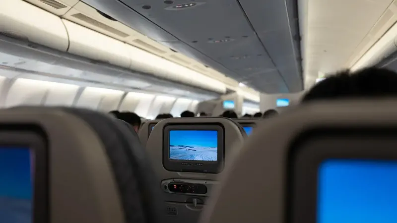 Interior of an airplane displaying in-flight entertainment screens and passenger seats.