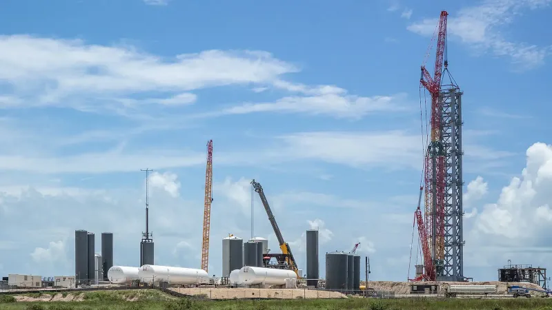 Los tanques de apoyo al suelo están en el medio y la torre de lanzamiento en construcción está a la derecha, rodeada de grúas.