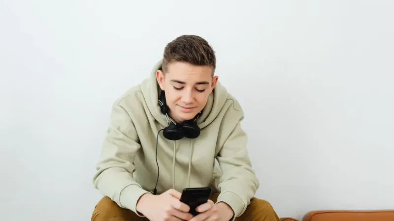 Young person enjoying technology, wearing casual clothes and headphones.