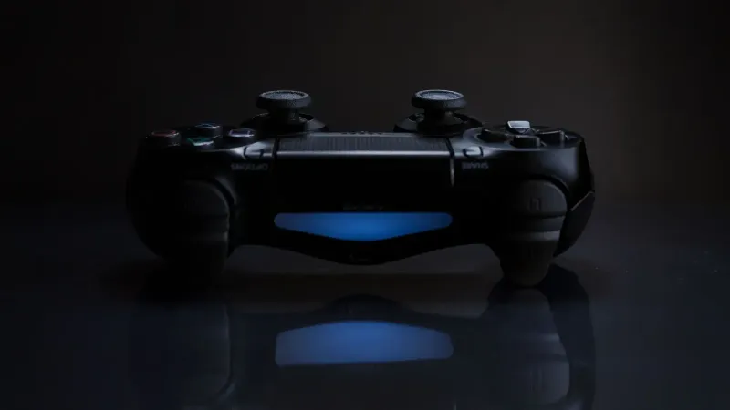 Primer plano de un controlador de juegos con una luz azul suave en un entorno oscuro.