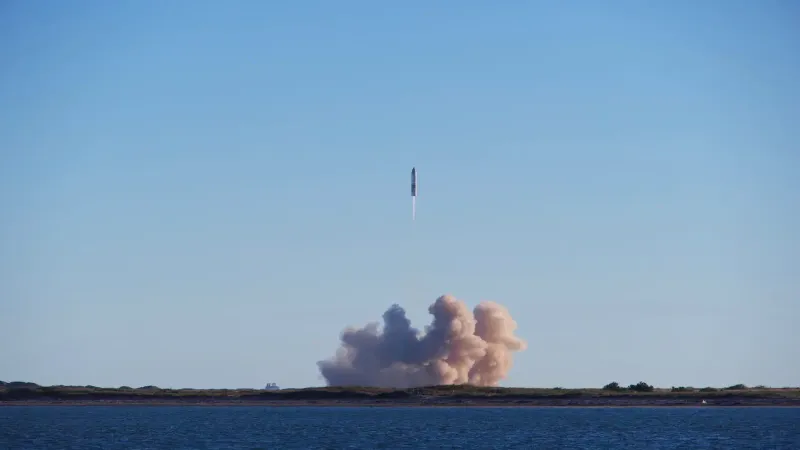 A rocket launch with smoke trails over South Padre Island, viewed across the ocean.