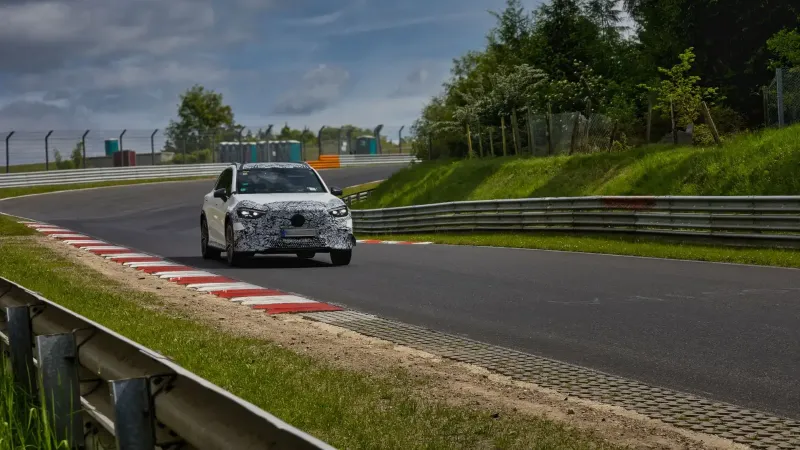 Coche deportivo camuflado conduciendo en la icónica pista de carreras de Nurburgring.