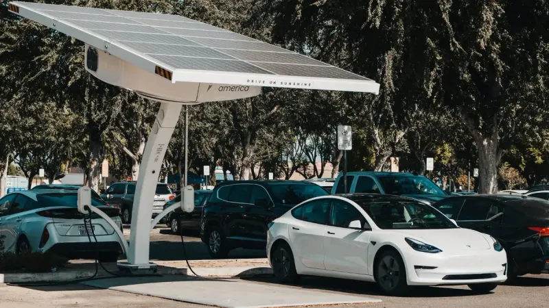 Coche eléctrico estacionado en una estación de carga solar al aire libre, destacando la energía renovable y la innovación.