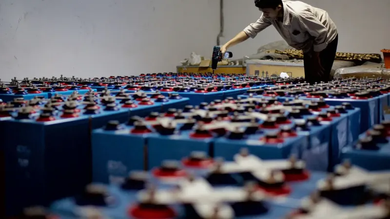 Un trabajador revisando muchas baterías industriales dentro de una instalación. Entorno interior, industrial.
