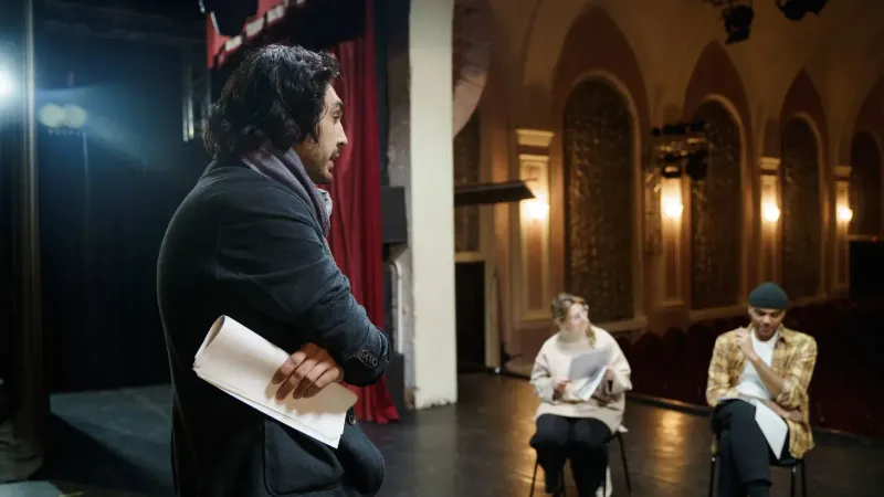 Actores ensayando en el escenario en un auditorio de teatro vintage con un director observando.