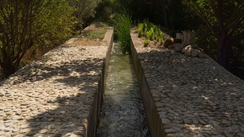 Cobblestone aqueduct with lush vegetation in Mula, Región de Murcia, Spain.