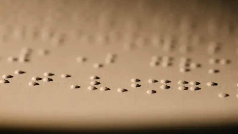 Toma macro de puntos braille en relieve en papel, ilustrando la lectura táctil para personas con discapacidad visual.