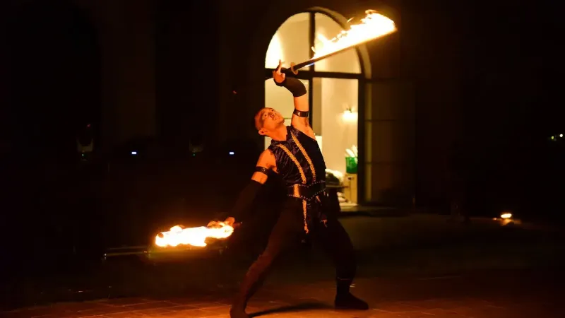 Intérprete de fuego dinámico bailando con llamas en un espectáculo nocturno.