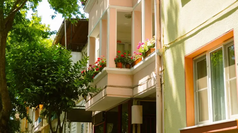 Balcón europeo iluminado por el sol adornado con flores de colores, creando una encantadora escena residencial en la calle.