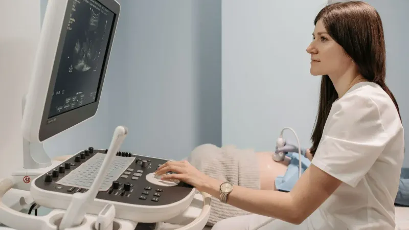 Una doctora que realiza un examen de ultrasonido en una clínica médica, centrándose en la atención al paciente.
