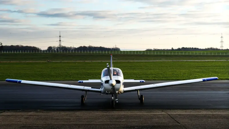 Un pequeño avión de hélice estacionado en una pista al aire libre al atardecer.