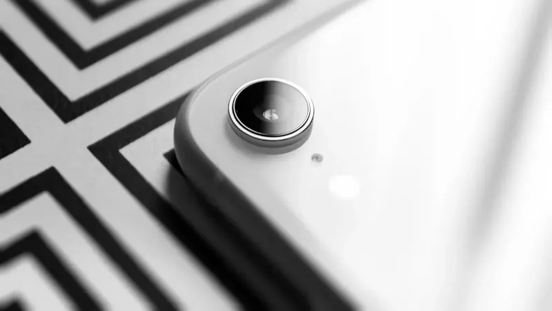 Black and white close-up capturing the elegance of a smartphone camera lens against a geometric background.