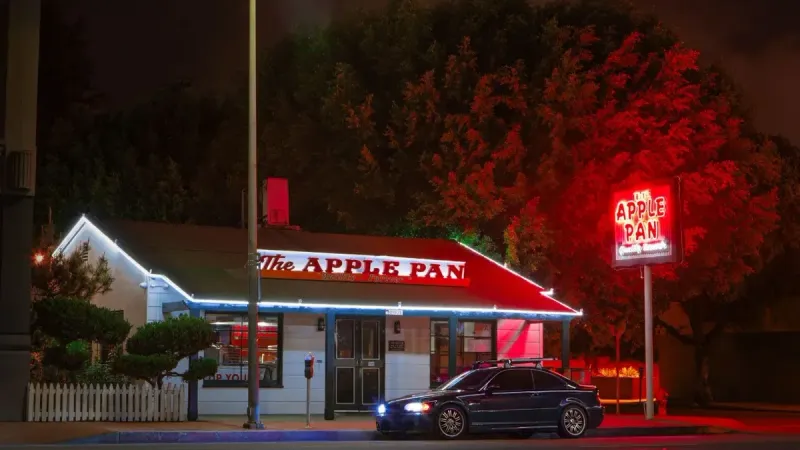 Captivating night shot of The Apple Pan, a famous diner in Los Angeles, with a BMW E46 parked in front.