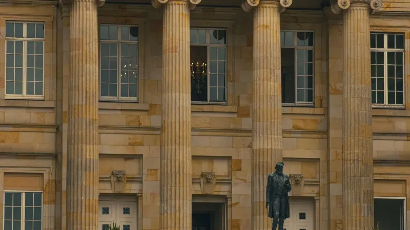 Vista elegante de un edificio clásico con pilares y una estatua en la entrada.