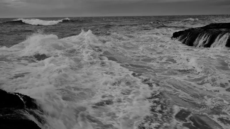 Las poderosas olas chocan contra los acantilados rocosos en la costa de Oregón, capturados en blanco y negro.