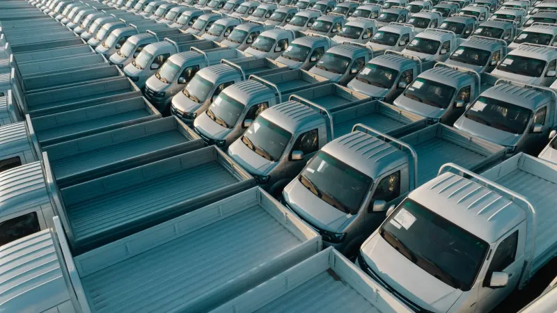 Toma aérea de varias camionetas plateadas alineadas en filas, mostrando simetría y producción industrial.