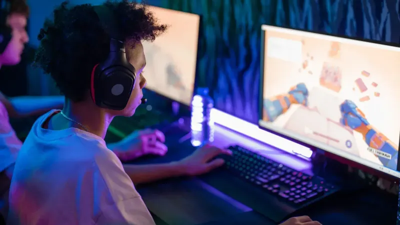 Jugadores adolescentes absortos en un juego de computadora en línea en una sala de juegos vibrante y moderna.