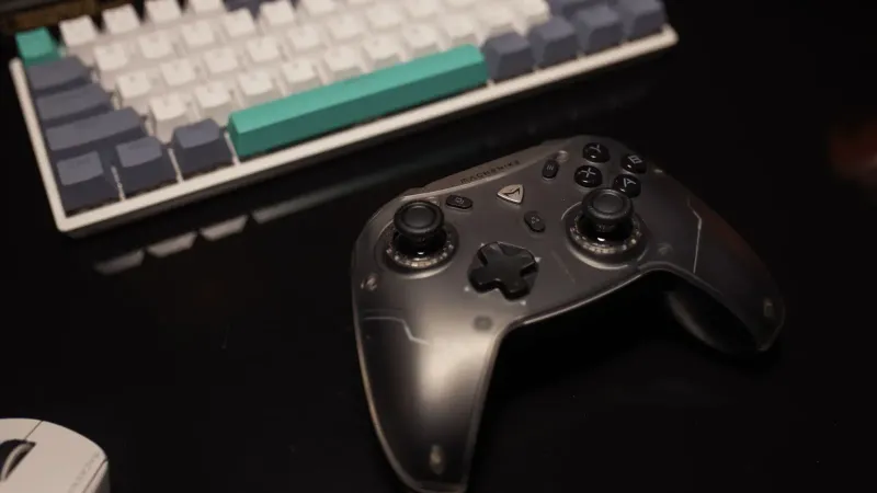 Primer plano de un controlador de juegos en un escritorio con teclado y mouse, perfecto para los jugadores.