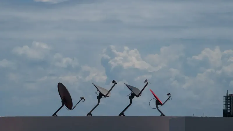 Cuatro antenas parabólicas en una azotea contra un cielo nublado en Cancún, México.